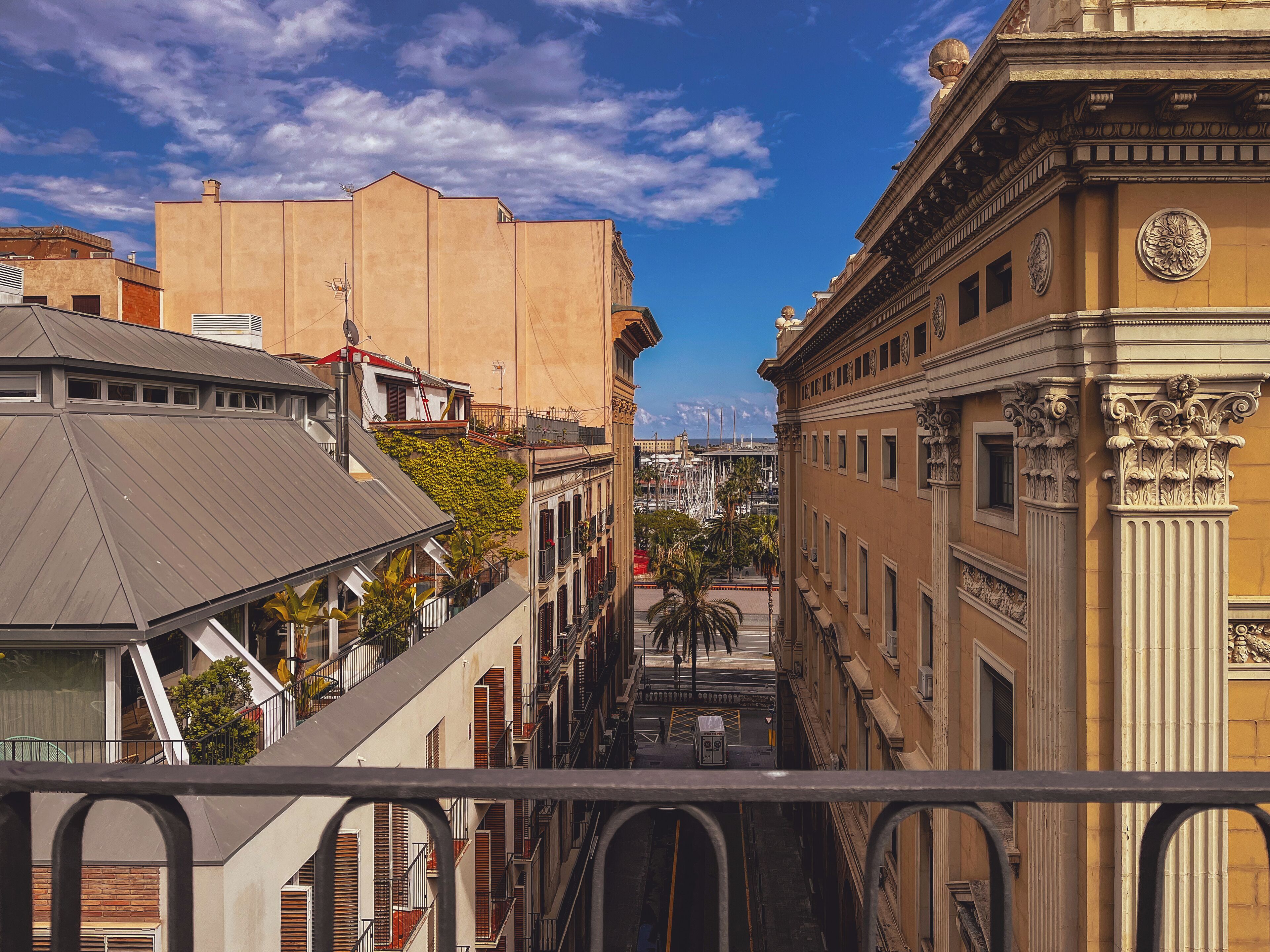 A view of a city street with buildings, including a yellow building with ornate columns and a balcony.