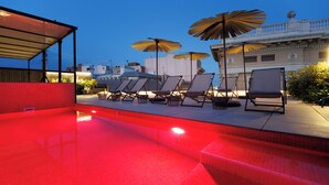 A rooftop pool area with lounge chairs and umbrellas, surrounded by buildings. - Hotel La Pau  (Barcelona)