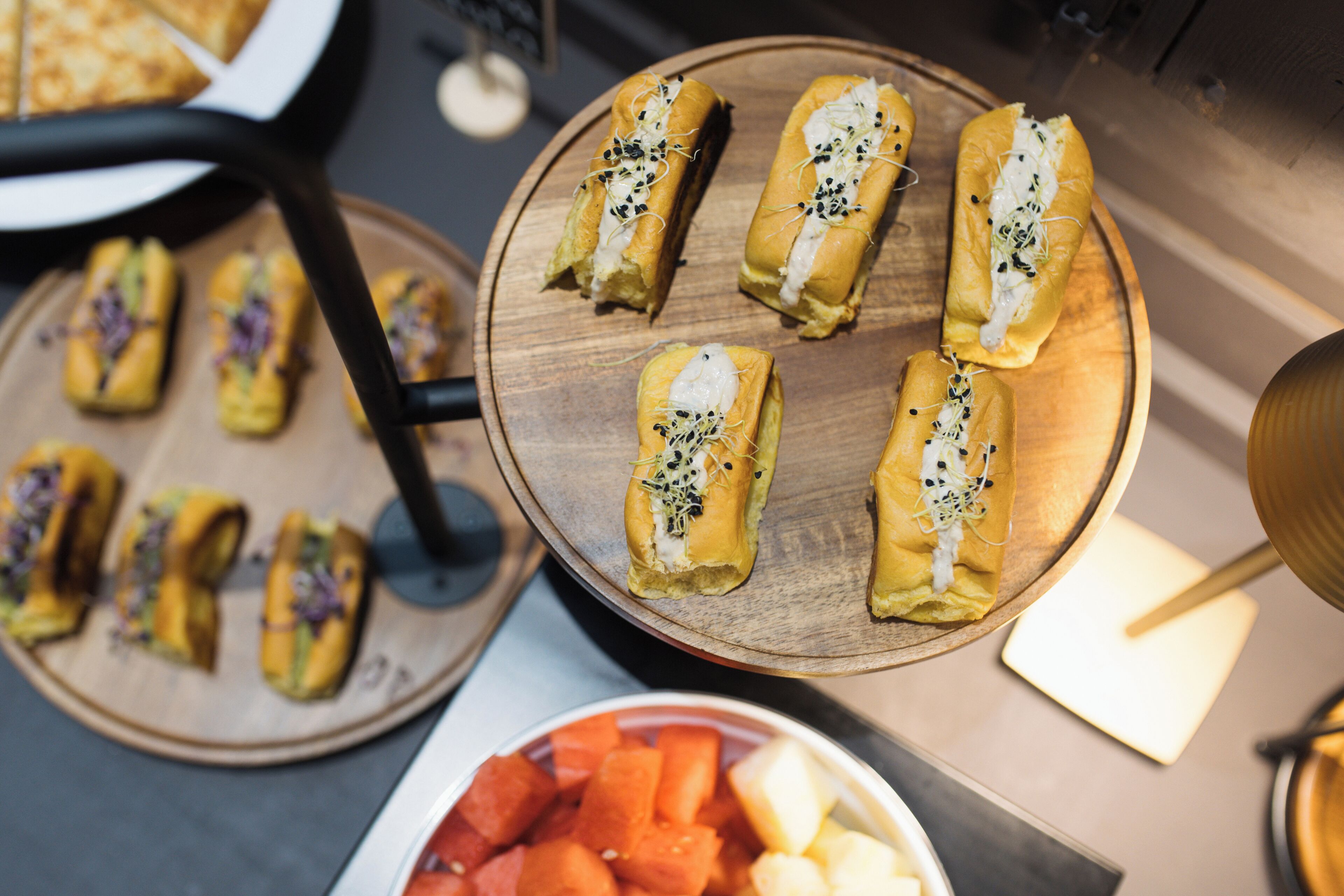 A wooden serving tray with several pastries topped with white cream and seeds.