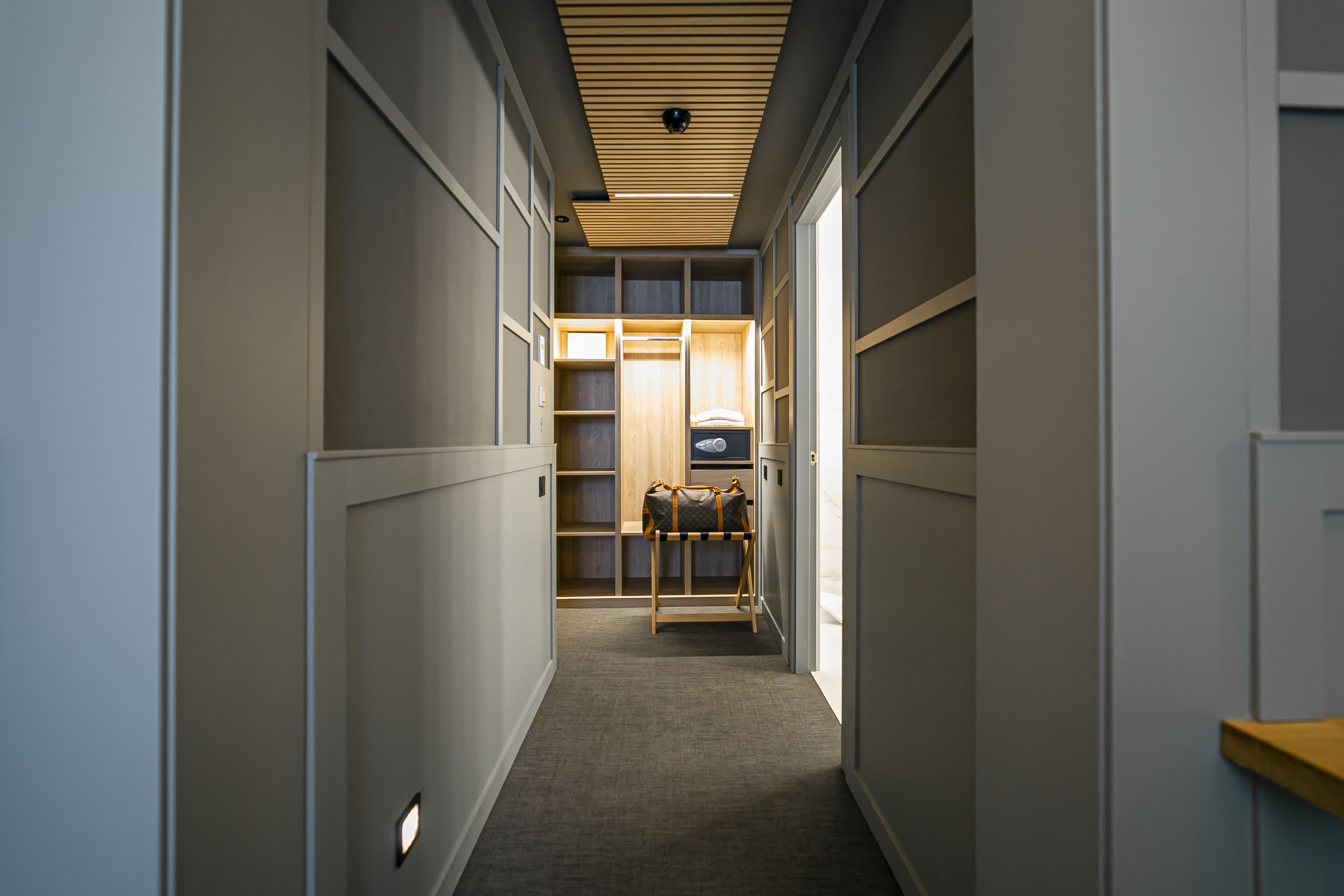 A narrow hallway with built-in shelving units and a wooden ceiling.