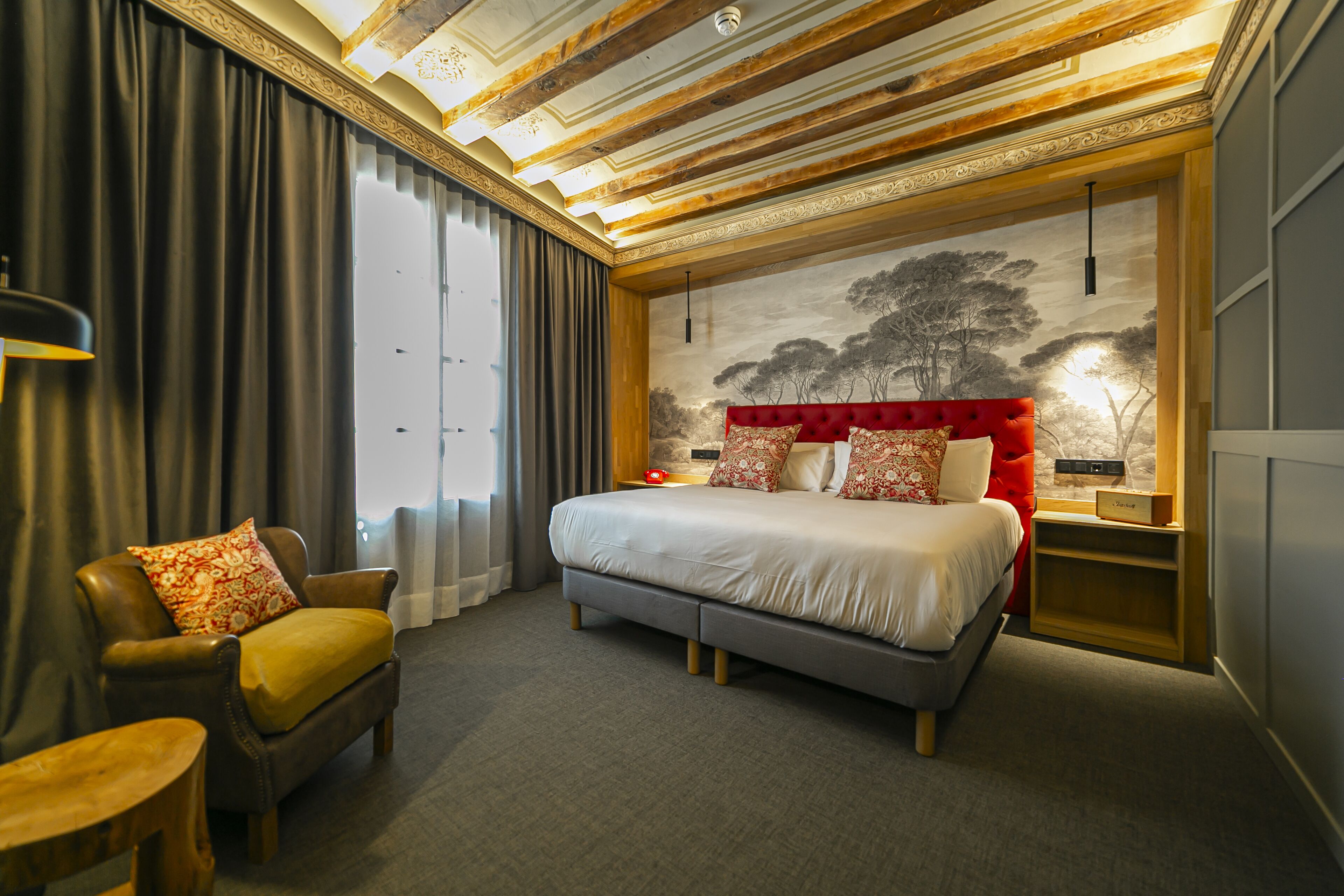 Een moderne hotelkamer met een groot bed, een leren fauteuil, een klein tafeltje en een muurschildering.