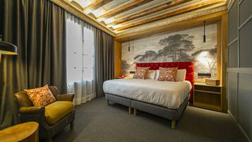 Een moderne hotelkamer met een groot bed, een leren fauteuil, een klein tafeltje en een muurschildering.