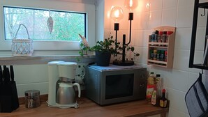 A modern kitchen with a window, a microwave, a kettle, and a spice rack.