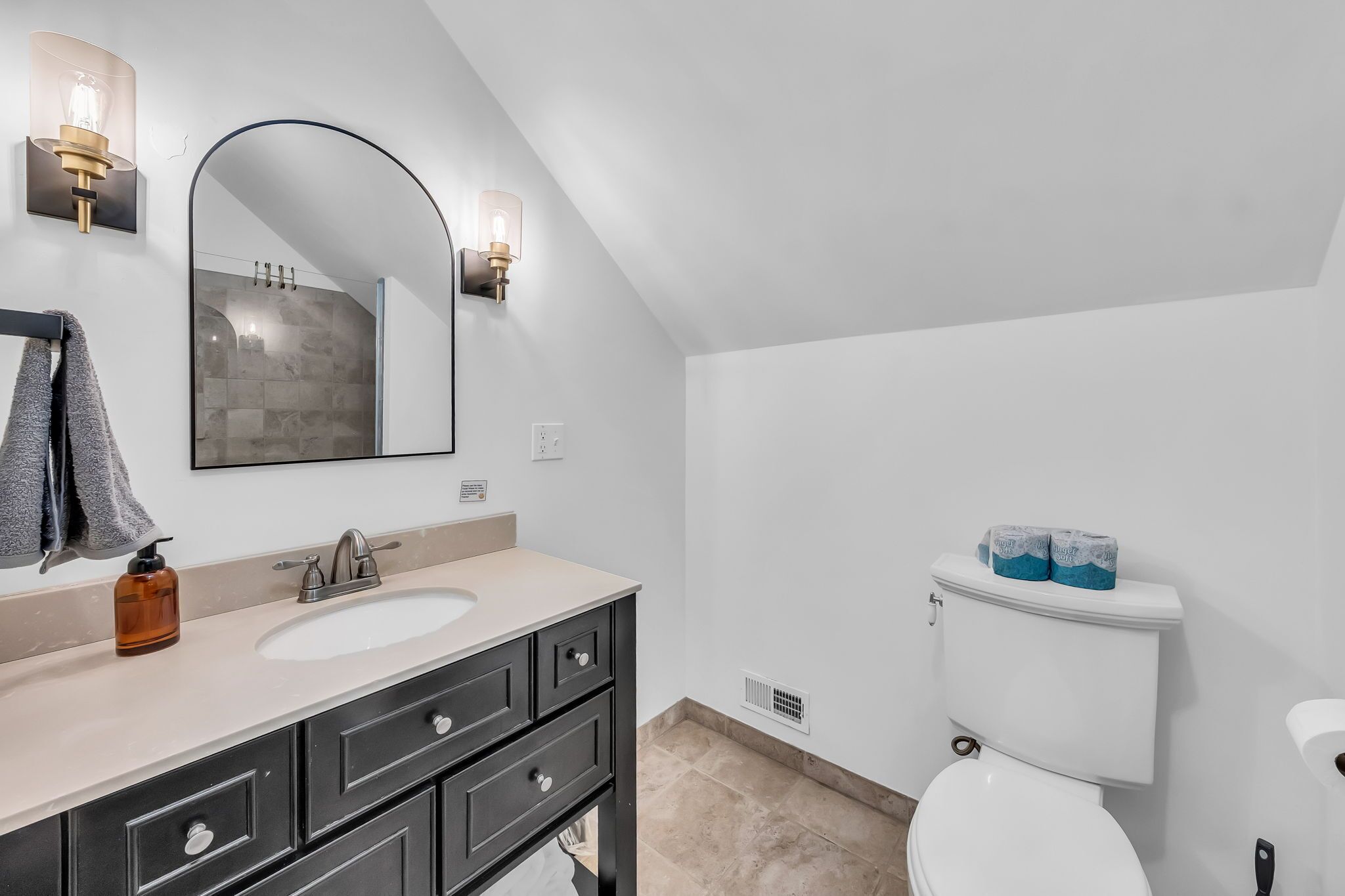 Une salle de bain moderne avec un grand miroir, un lavabo et des toilettes.