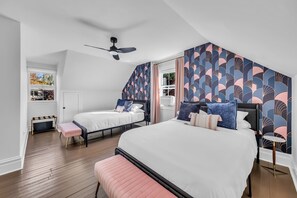 A bedroom with two beds, a ceiling fan, and a window with a view of trees. - The Laughing Boar, perfectly located downtown (Hermann)
