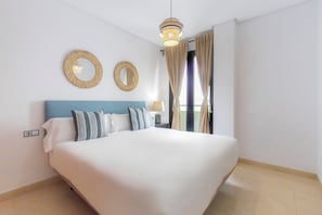 A neatly arranged bedroom with a large bed, two wall mirrors, and a hanging light fixture. - APARTAMENTOS MOON DREAMS PUERTO (El Puerto de Santa Maria)