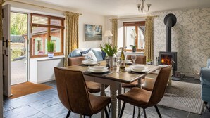 A dining area with a table set for four, a fireplace, and a view of the outside. - A stone cottage that sleeps 3 guests  in 1 bedroom (Combe Martin)