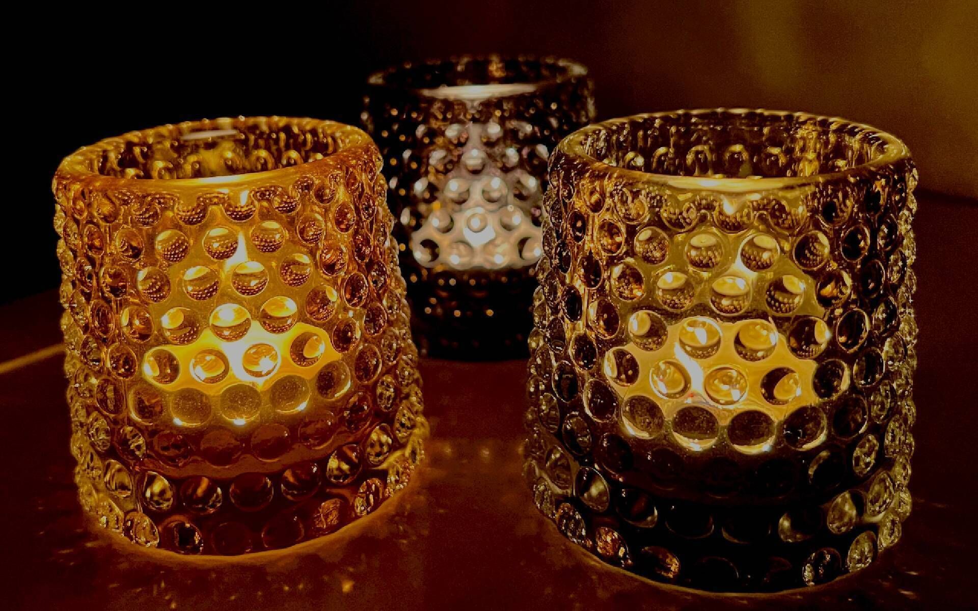 Three candle holders with textured surfaces and reflective surfaces.