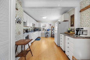 Una cocina estrecha con armarios blancos, un banco de madera y un microondas.