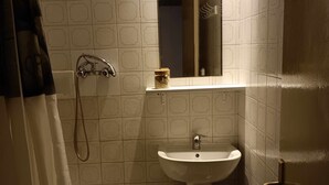 A small bathroom with a white sink, a mirror, and a shower.