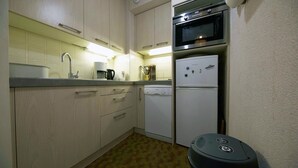 A compact kitchen with a dishwasher, a microwave, and a refrigerator. - Nice studio on the seafront (Arcachon)