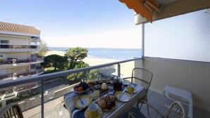 A balcony with a table set for breakfast overlooking a beach. - Nice studio on the seafront (Arcachon)
