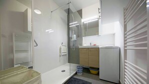 A modern bathroom with a glass shower enclosure, a white sink, and a small mirror above the sink. - Nice studio on the seafront (Arcachon)