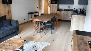 Moderni keittiö, jossa on tummat kaapit, puinen ruokapöytä ja musta työtaso.