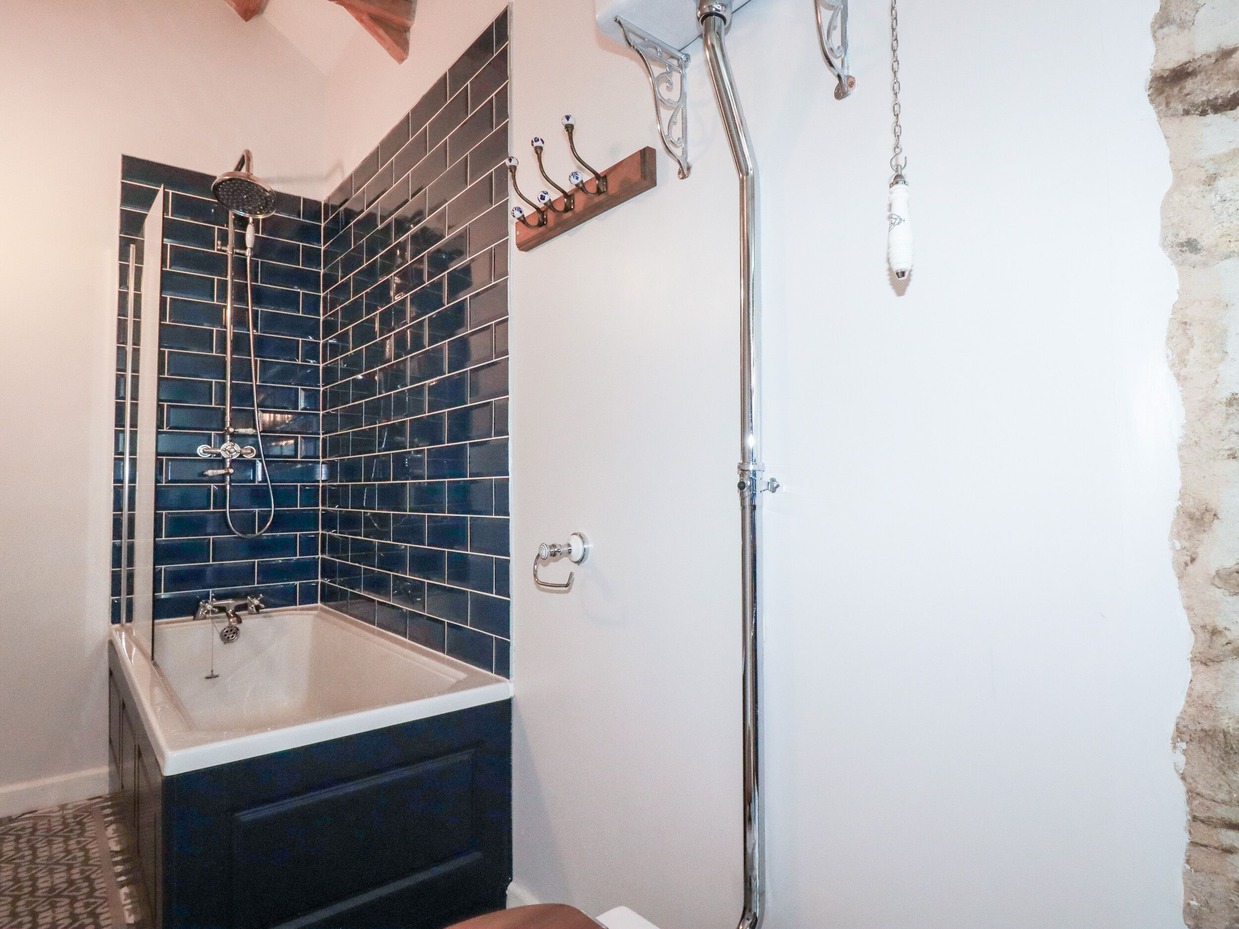 A bathroom with a bathtub, a shower, and a tiled wall.