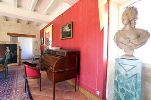 A room with a red wall, a wooden desk, a bust sculpture, and a framed painting. - `Venise` - luxurious apt on boutique wine estate (Fougueyrolles)