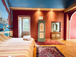 Un dormitorio con cama, ventana, cómoda y espejo.