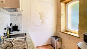 A kitchen with a tiled backsplash, a small window, and a microwave.