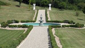 A landscaped garden with a central fountain, symmetrical pathways, and manicured lawns.