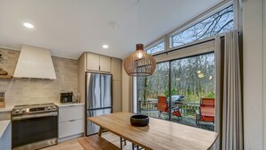 Eine moderne Küche mit großem Fenster, einem Esstisch und einem eingebauten Backofen.