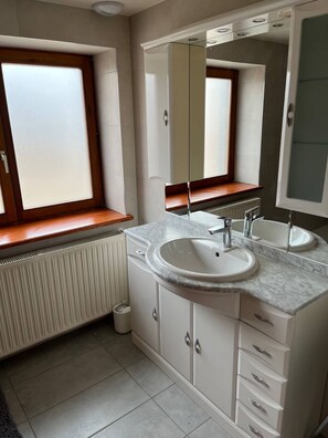 Ein modernes Badezimmer mit einem großen Fenster, einem Waschbecken und einem Spiegel.