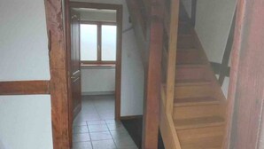 A hallway with a wooden staircase leading to a room with a window.