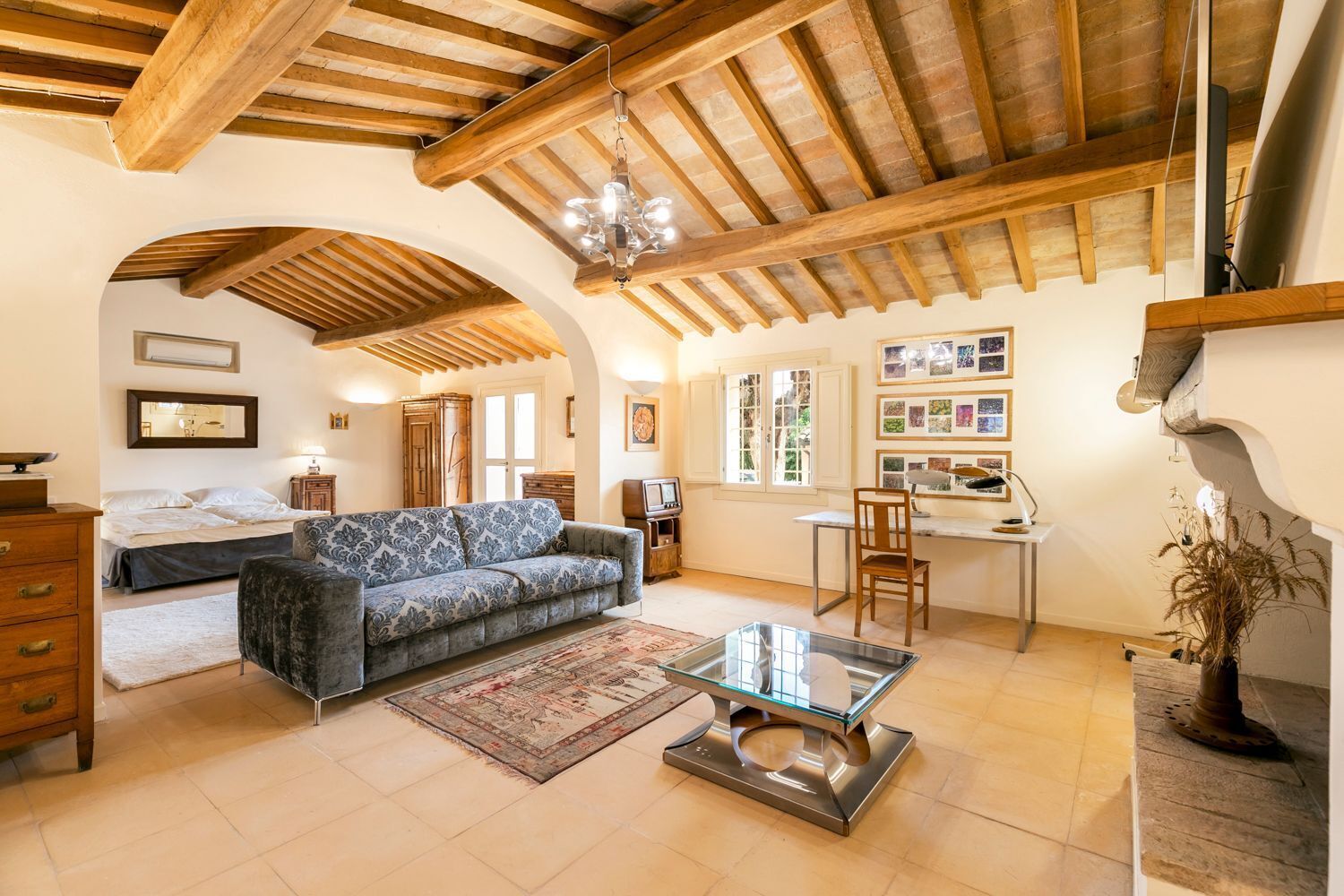 A spacious living room with a sofa, a glass coffee table, and a fireplace.