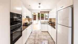 A modern kitchen with white cabinetry, a black oven, and a white refrigerator. - Villa Chrysos - Three Bedroom Villa, Sleeps 6 (Tala)