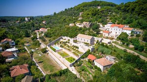 An aerial view of a hillside village with traditional stone buildings, a central courtyard with a pool, and lush greenery. - Villa Reverie - Seven Bedroom Villa, Sleeps 14 (Sudurad)