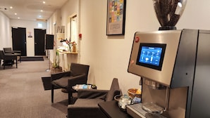 A modern lounge area with a coffee machine, seating, and a sign indicating a restaurant. - Banegaardshotellet (Vojens)