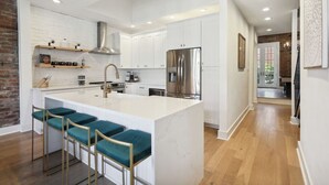 A modern kitchen with white cabinetry, a stainless steel refrigerator, and a central island with bar stools.