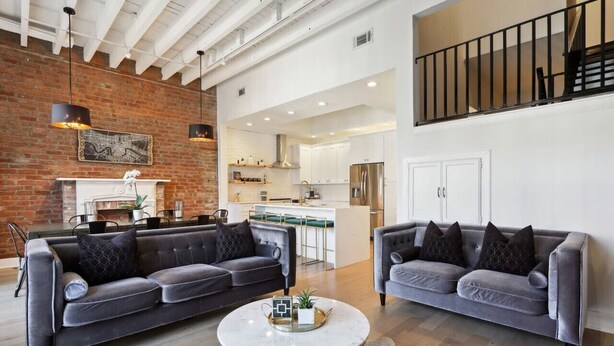 A spacious living area with two grey sofas, a white coffee table, and a brick wall.