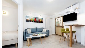 A modern living room with a sofa, a coffee table, and a TV mounted on the wall. - Apartment Amici (Rovinj)