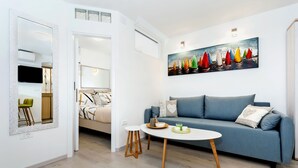 A modern living room with a blue sofa, a round coffee table, and a painting of sailboats on the wall. - Apartment Amici (Rovinj)