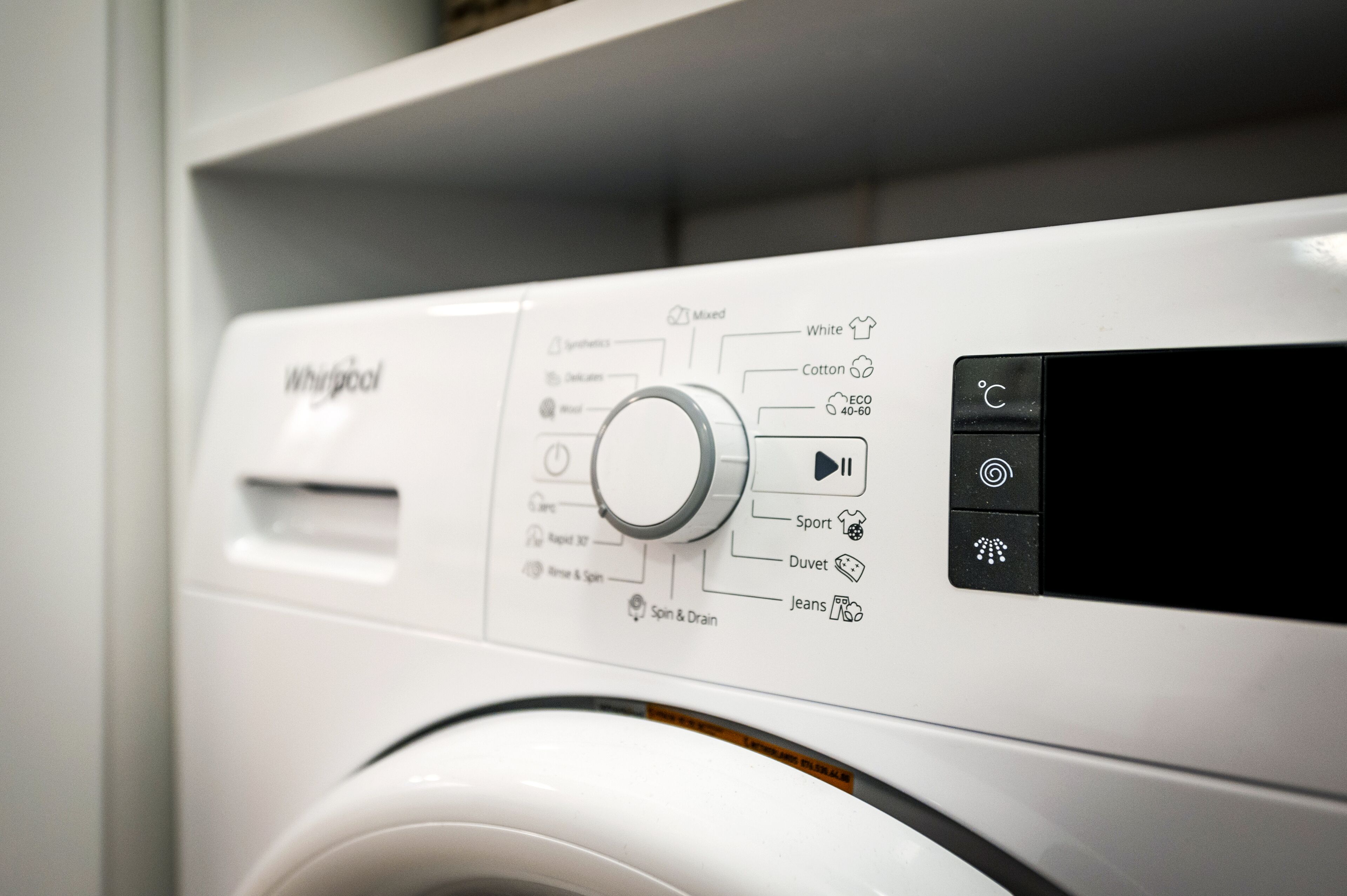 Vue de face d’un lave-linge Whirlpool, avec un panneau de commande doté de divers réglages et d’un écran numérique.