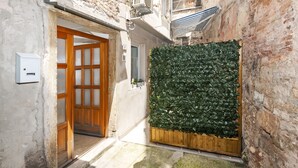 A narrow alleyway with a wooden door and a wall covered in green foliage. - Apartment Amici (Rovinj)