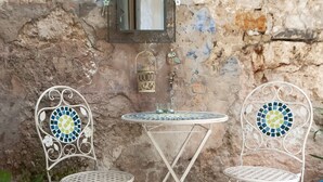 A small outdoor seating area with two metal chairs and a round table, set against a textured stone wall. - Apartment Amici (Rovinj)