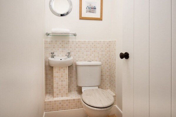 A bathroom with a toilet, sink, and a framed picture on the wall. - Beautiful renovated Stone Cottage with enclosed Garden and Free Wifi. (Berwick-upon-Tweed)
