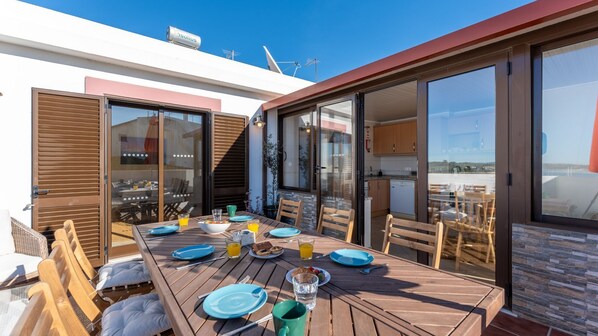 An outdoor dining area with a wooden table set for breakfast, surrounded by chairs. - Maravilhoso Duplex T3 com Terraço by LovelyStay (Alvor)