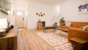 Un salon moderne avec un plancher en bois, un canapé, une table basse et un tapis.