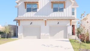 Une maison à deux étages avec un garage, une pelouse devant et un ciel dégagé.