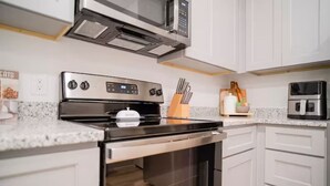 Une cuisine moderne dotée d’appareils électroménagers en acier inoxydable, de meubles blancs et d’un plan de travail en granit.