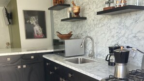 A modern kitchen with a marble backsplash, stainless steel appliances, and black cabinetry.
