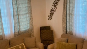 A living room with two sofas, a decorative wall piece, and a ceiling light fixture.