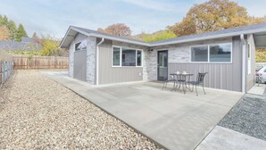 A two-story building with a patio area featuring a table and chairs. -  NEW Build-777 Hideaway (Grants Pass)