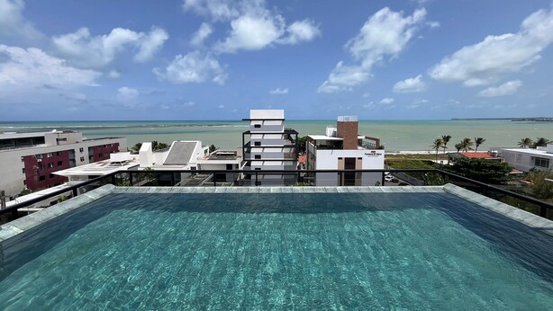 A rooftop infinity pool with a clear view of the ocean and a distant shoreline. - Flat Premium Ozean Home & Service - João Pessoa (João Pessoa)