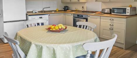 Una cocina compacta con mesa, sillas, microondas y hervidor.