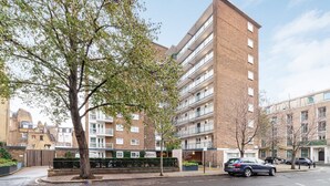 A multi-story residential building with a brick facade, balconies, and a gated entrance.