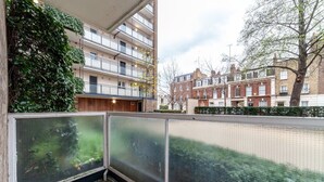 A balcony with a view of residential buildings and a tree.