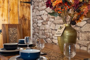 A dining table with a vase of autumn leaves and berries, a sign that reads "Bee happy," and various dishes and glasses.